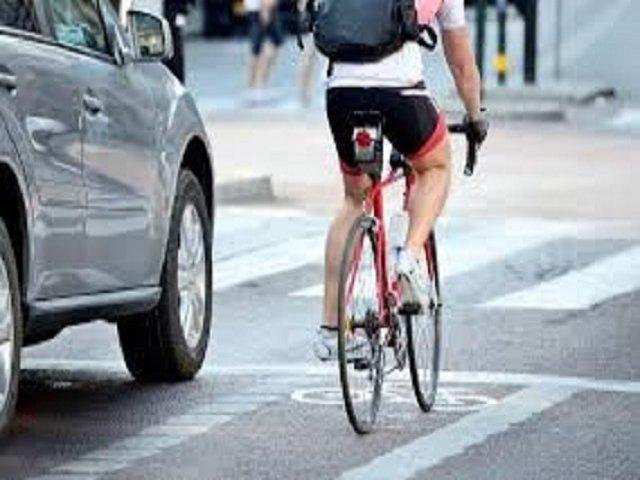 Cyclist in a cycle lane beside a car on the road